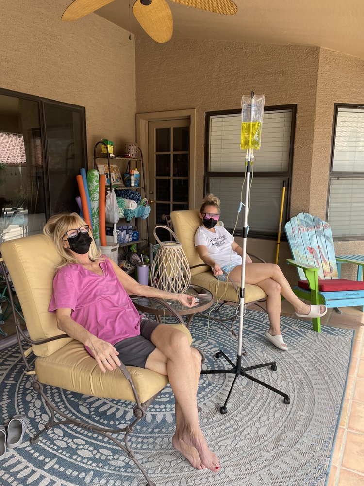 Two women relaxing on their porch while receiving IV therapy from our mobile service.