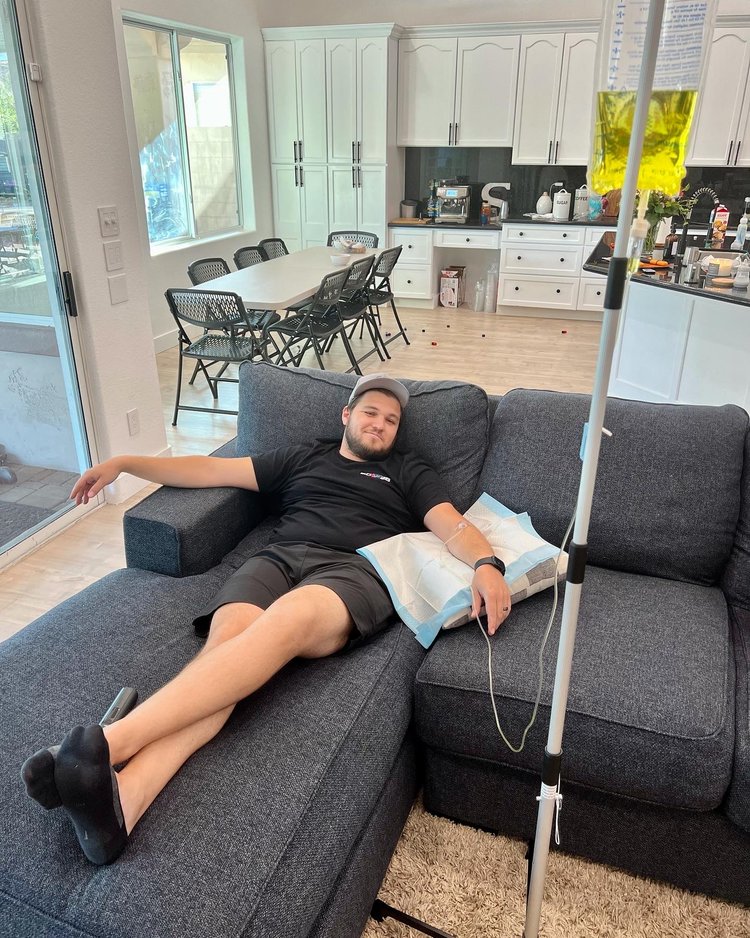 A man relaxing on his couch while receiving IV therapy in his home.