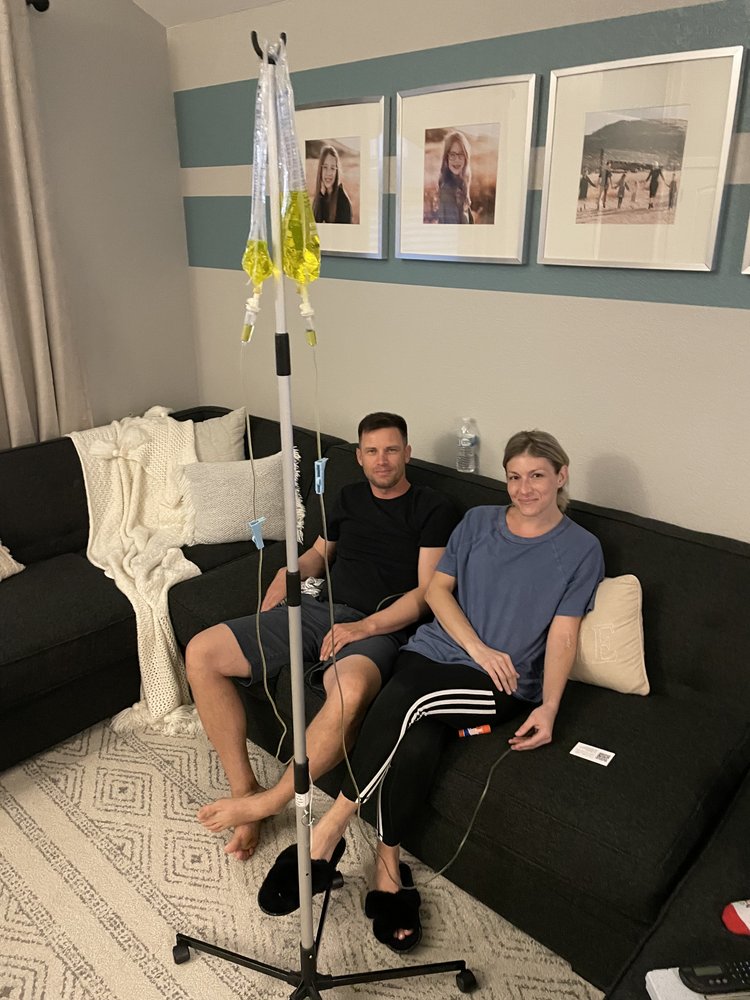 A couple sitting on their couch in their home receiving IV therapy together.