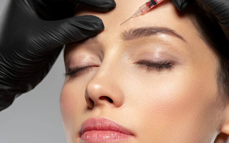 Woman receiving a wrinkle relaxer treatment to her forehead to reduce lines between the eyebrows.